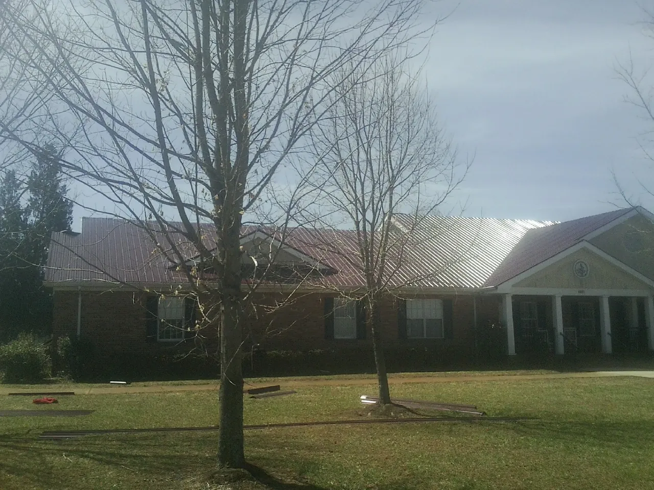 Red metal roof on a brick building seen from the front lawn in Hammondsport