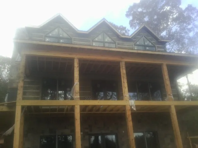 Dormers and porch framing on a large log home under construction — Roof Coating work by our crew in Hammondsport