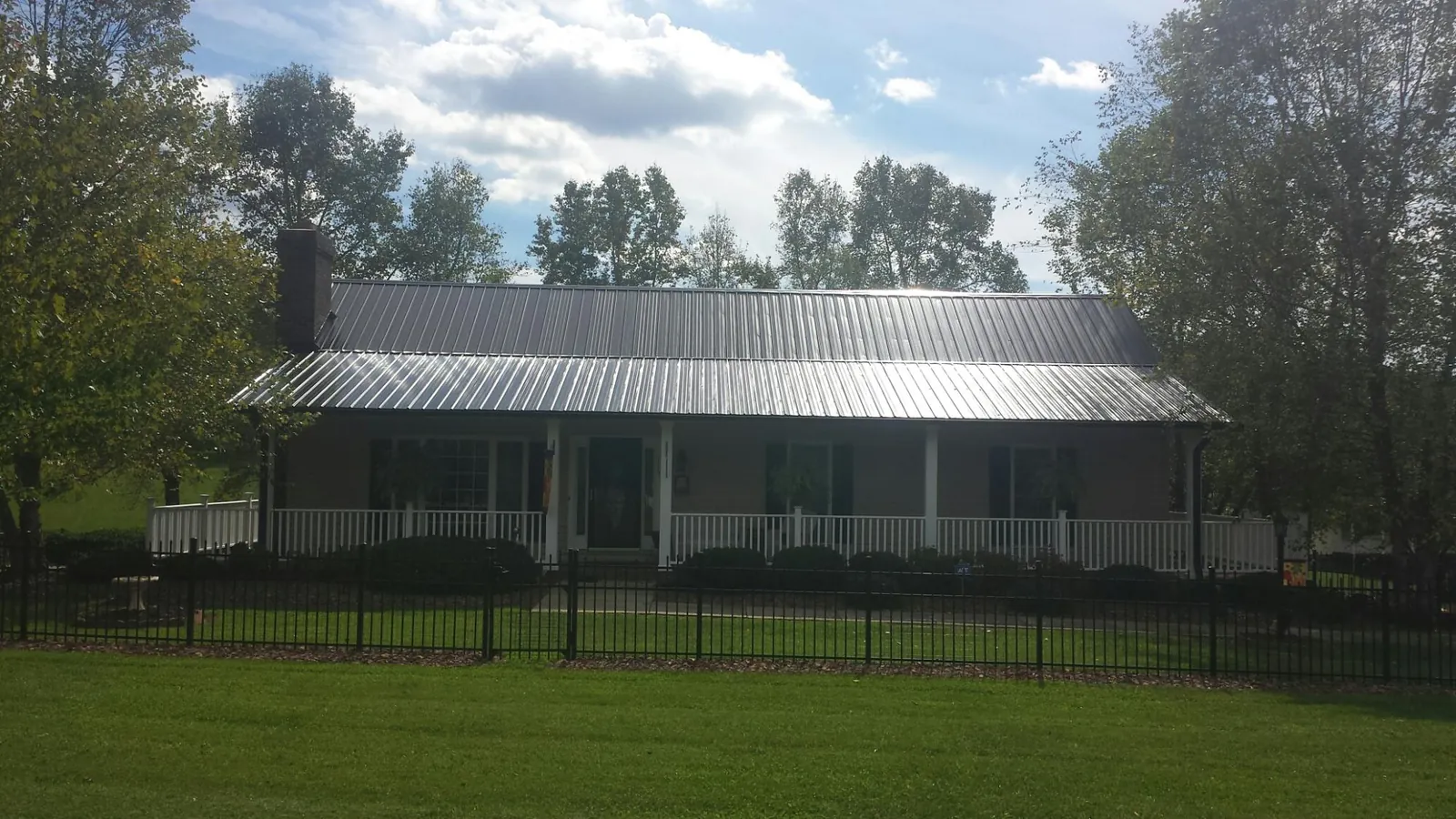 Gray metal roof on a brick ranch with a full width front porch — Gutter Guard Installation work by our crew in Hammondsport