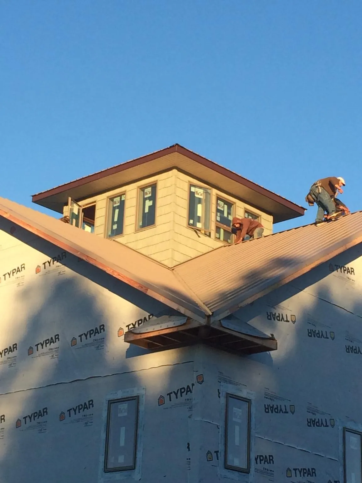 Roofers working around a rooftop cupola on a new metal roof at sunset — Roof Waterproofing in Hammondsport by Roofing Brothers